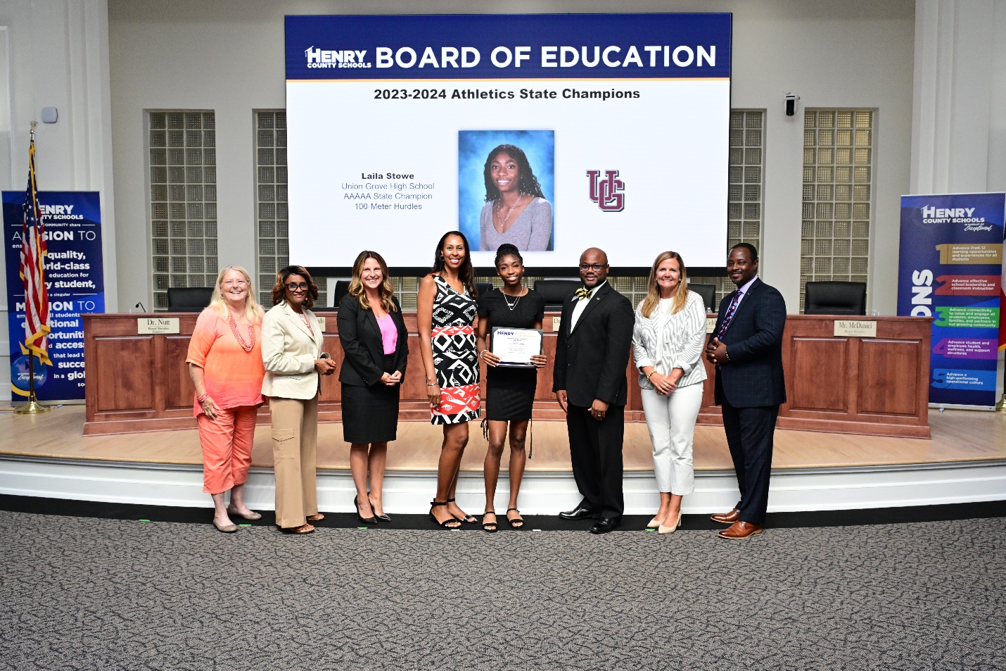 A group of people standing in front of a large screenDescription automatically generated